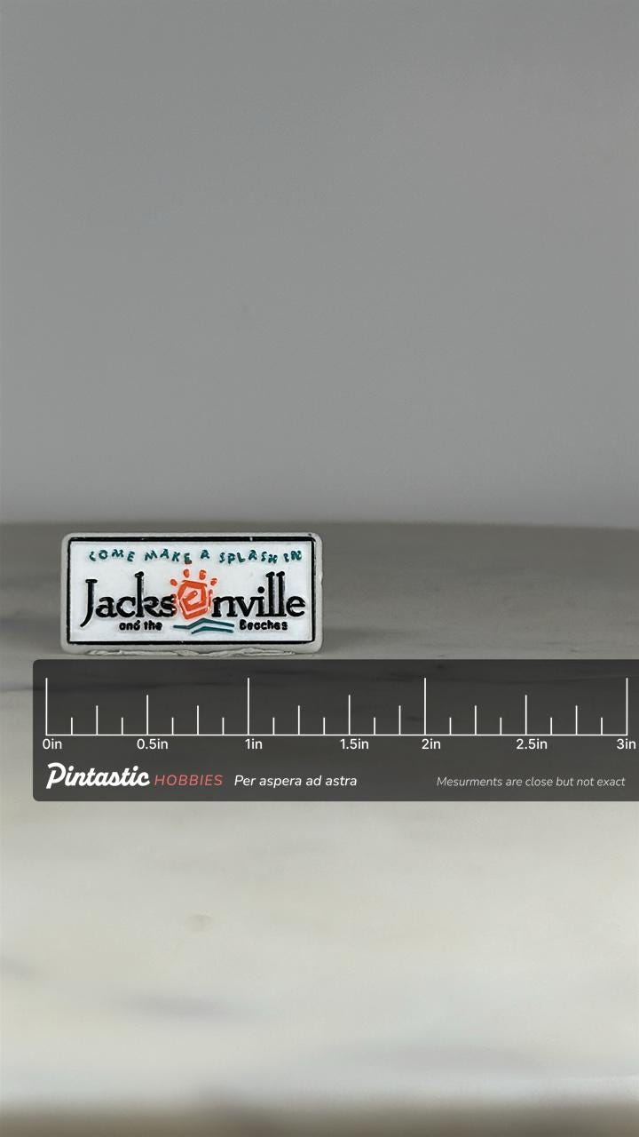 Jacksonville Souvenir Enamel Pin: White & Teal Tourist Badge - Retro Travel Accessory with ruler overlay for size reference