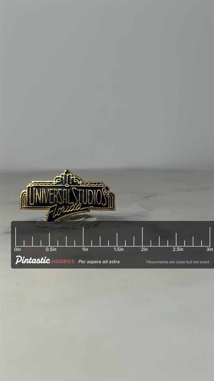Universal Studios Florida Pin: Black Gold Enamel - 90s Theme Park Accessory with ruler overlay for size reference
