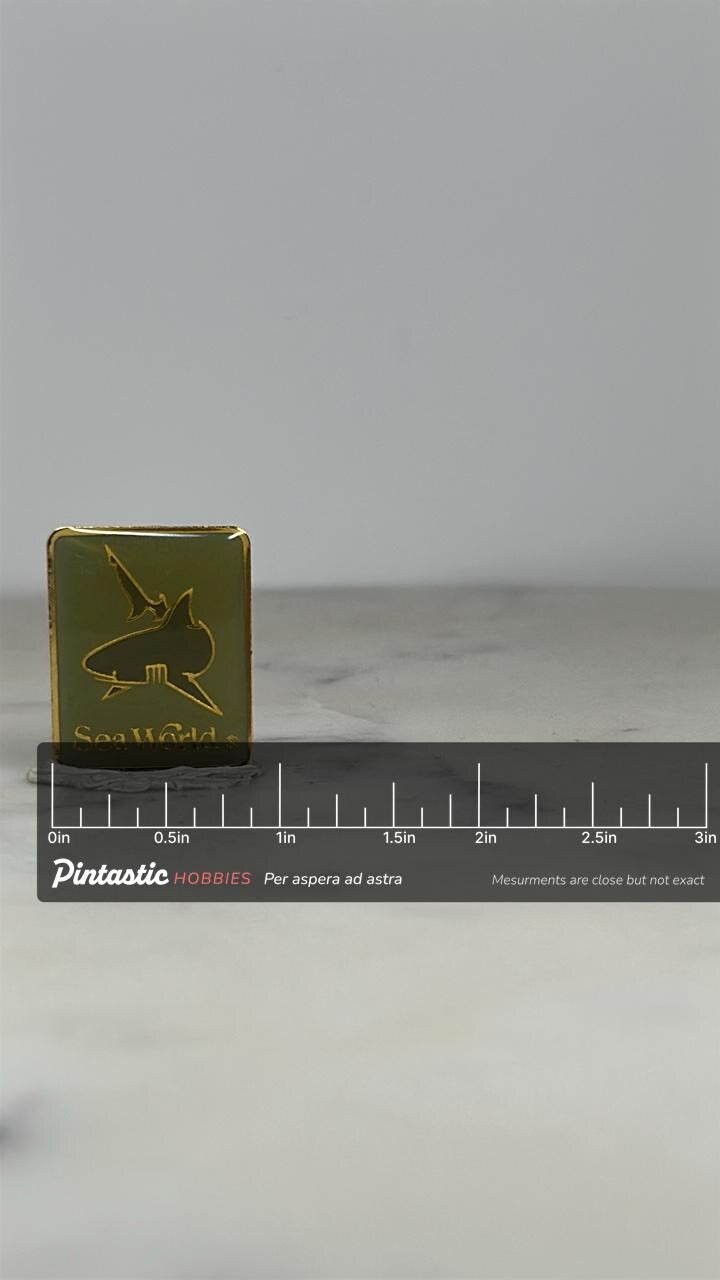SeaWorld Souvenir Pin: Gold Enamel Logo - Vintage Amusement Accessory with ruler overlay for size reference