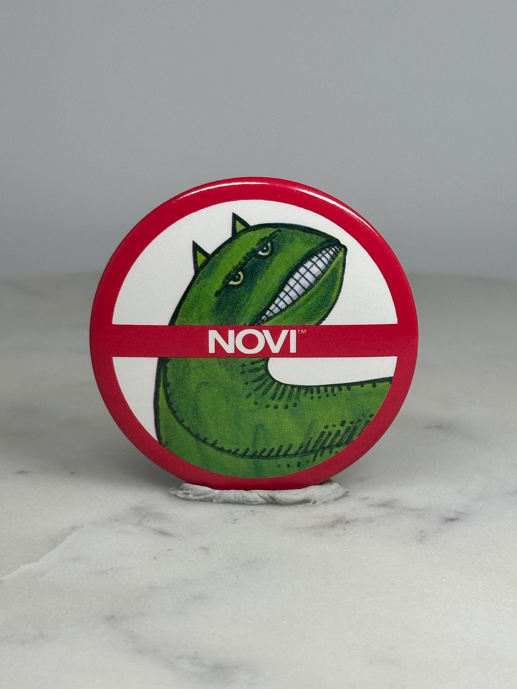 Novi Dinosaur Parody Pin: Red/White Finish - Retro Humor Accessory