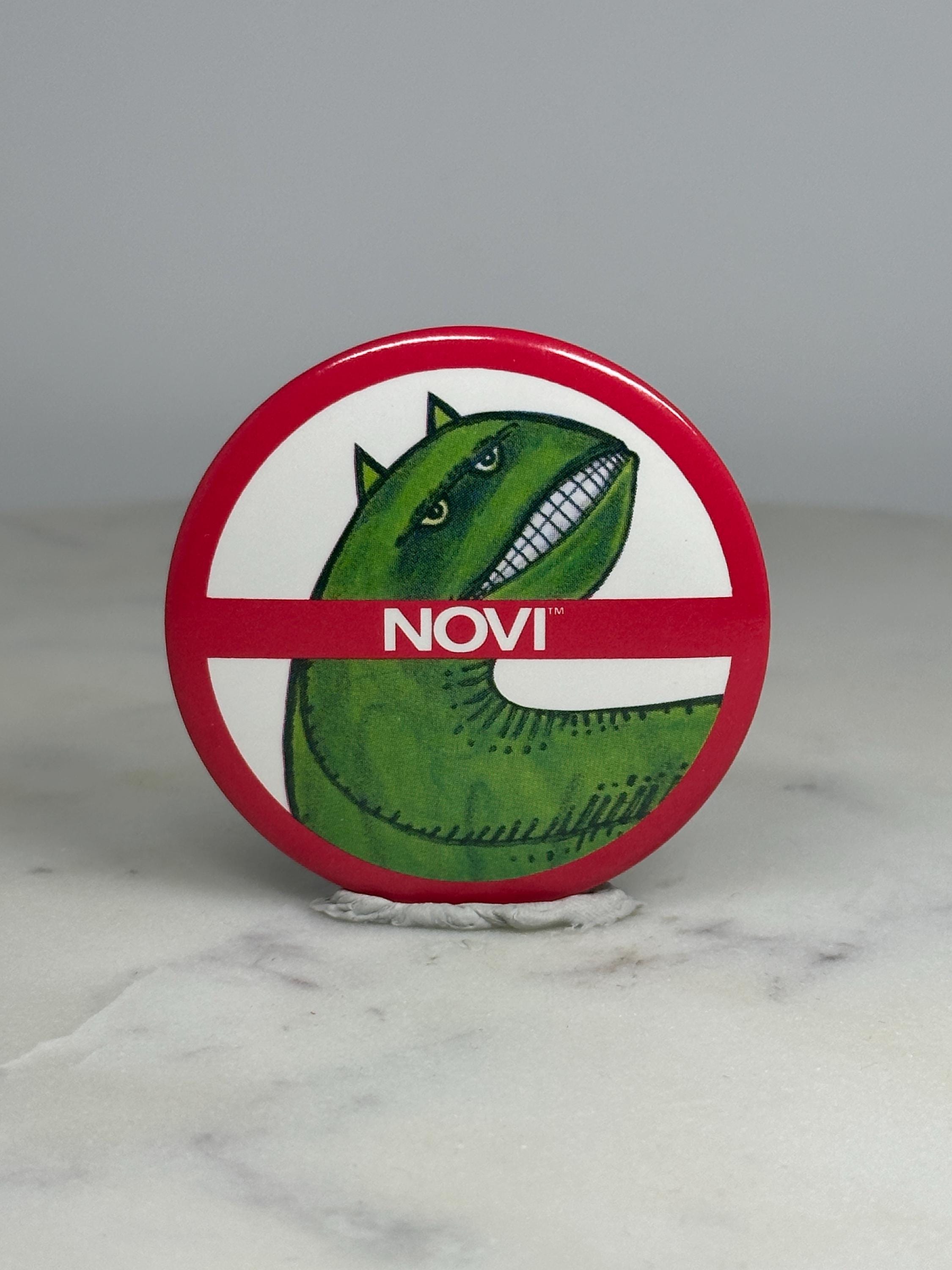 Novi Dinosaur Parody Pin: Red/White Finish - Retro Humor Accessory