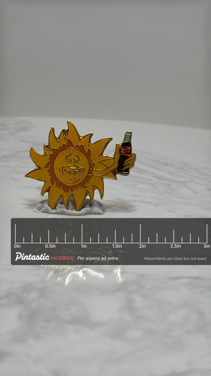Coca-Cola Sun Holding Drink Enamel Pin: Retro Yellow & Blue - 90s Summer Accessory with ruler overlay for size reference
