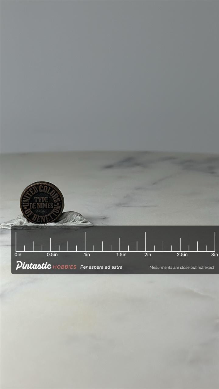 Vintage Benetton Logo Lapel Pin: Black Enamel - 1990s Fashion with ruler overlay for size reference