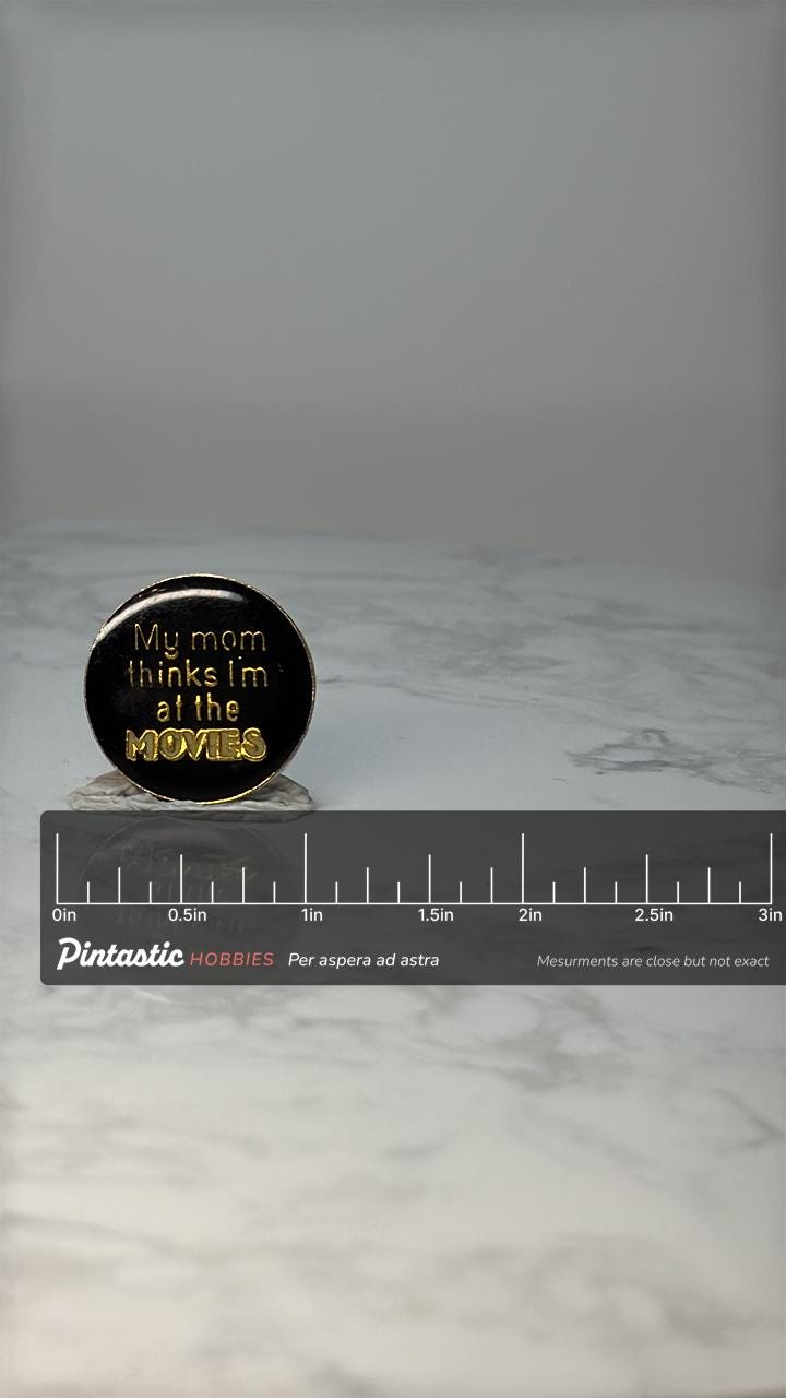 Vintage Movie Humor Lapel Pin: Black & Gold - 1980s Novelty Accessory with ruler overlay for size reference