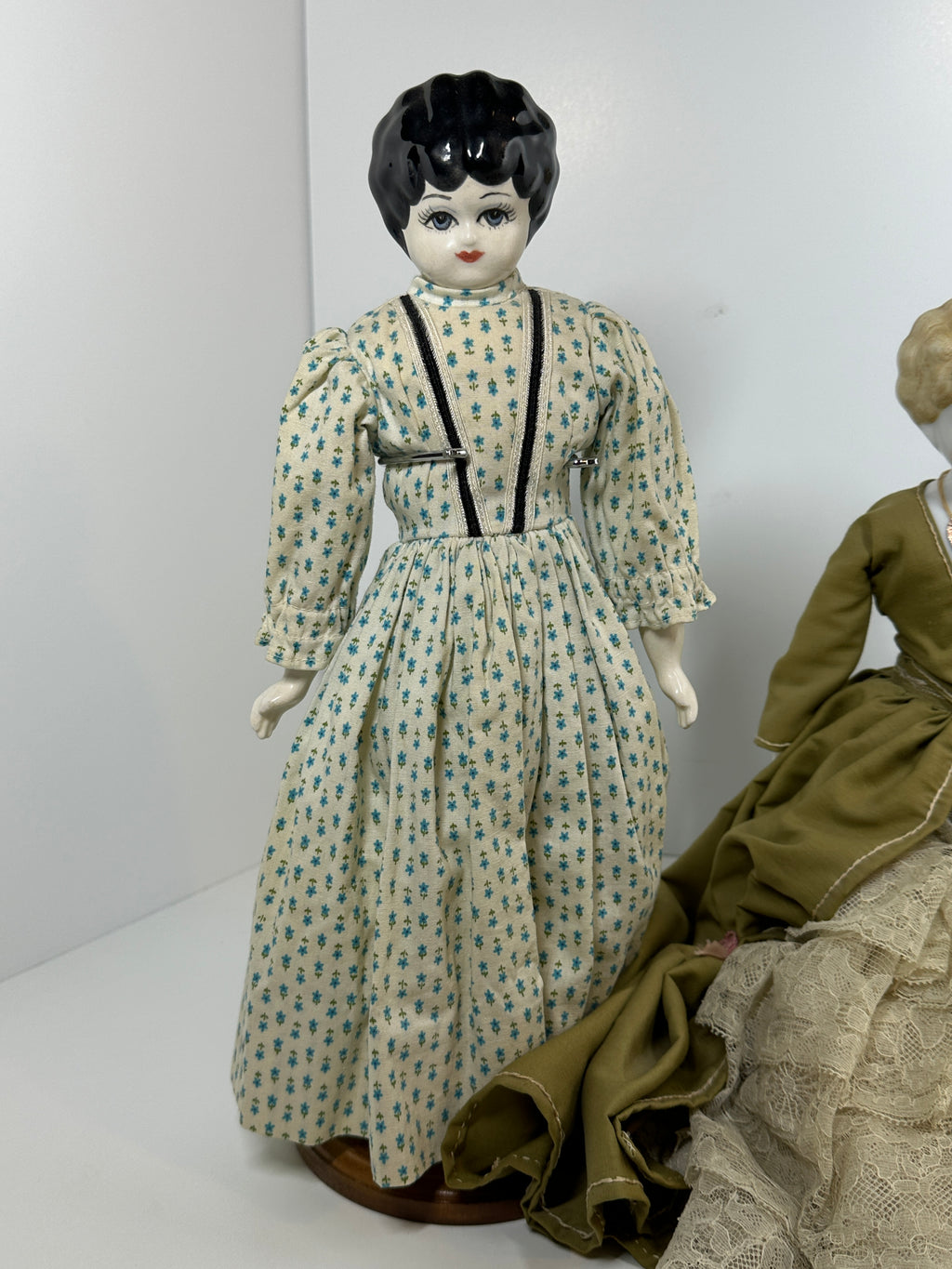 Vintage porcelain china head doll set with two dolls in period clothing, one standing and one seated with lace dress