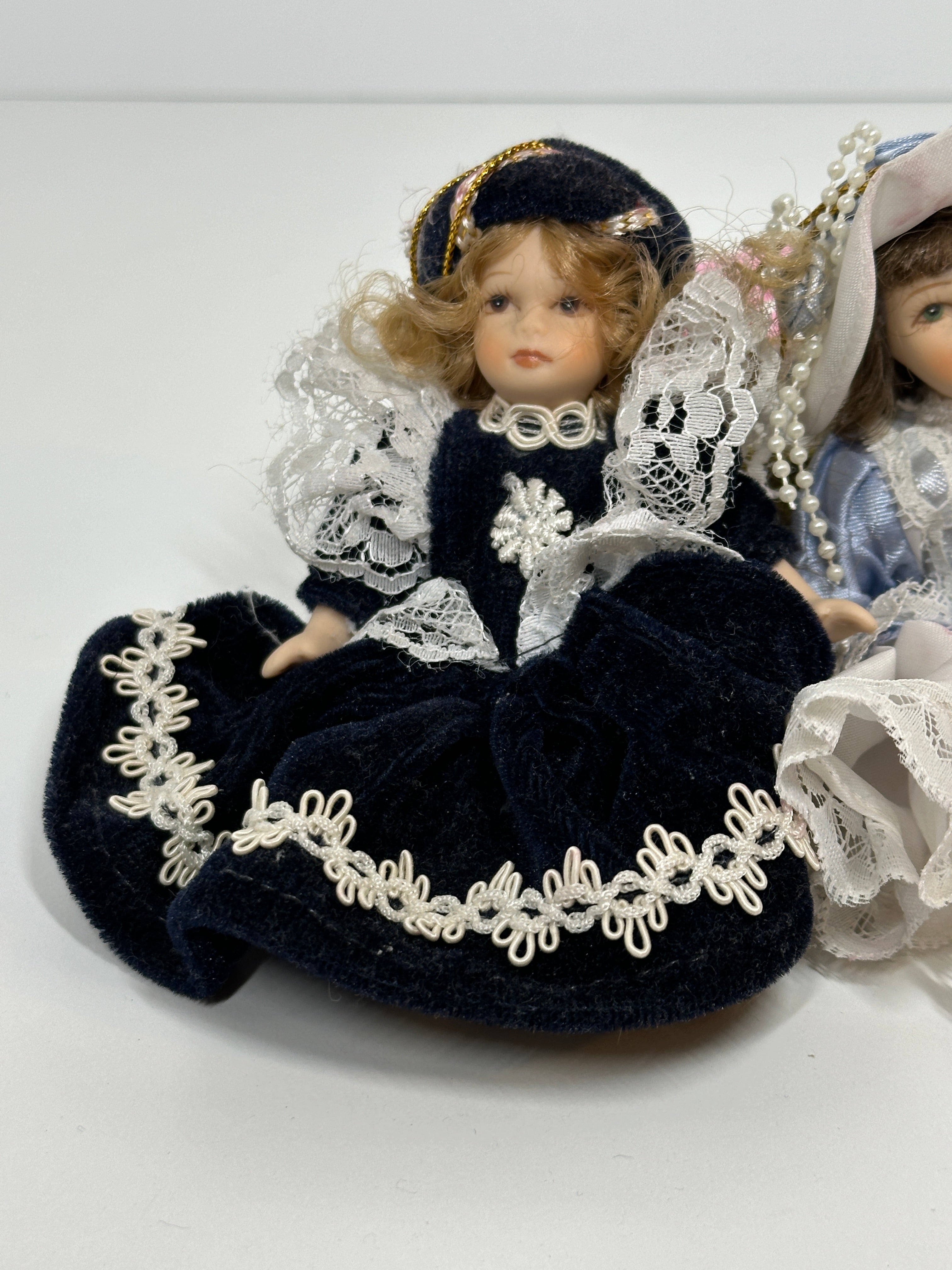 Set of two miniature porcelain dolls wearing blue vintage style lace dresses with painted faces
