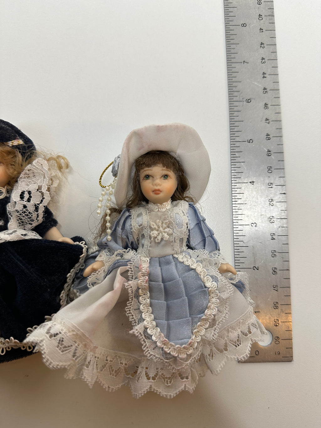 Set of two miniature porcelain dolls wearing blue vintage style lace dresses with painted faces