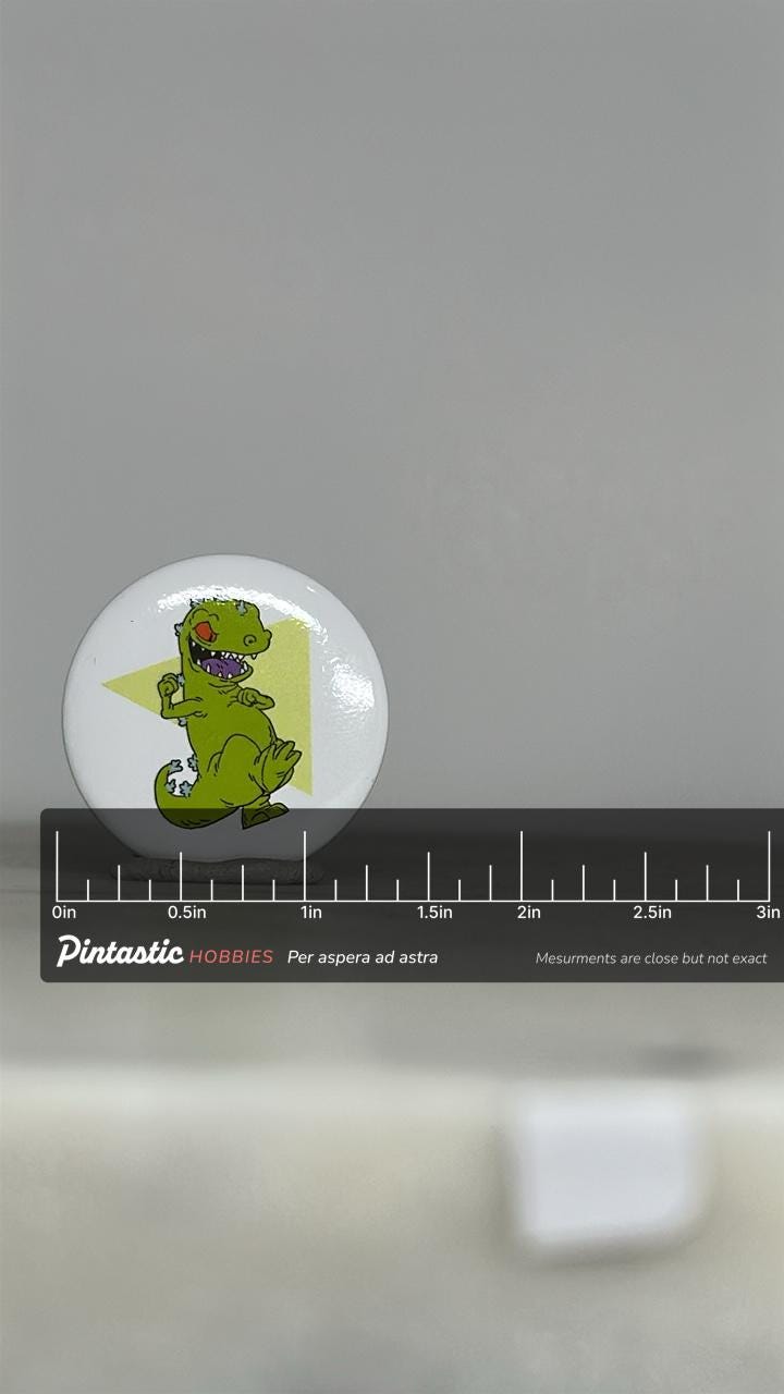 Vintage Reptar Button Pin: Glossy White Finish - 90s Nickelodeon Accessory with ruler overlay for size reference