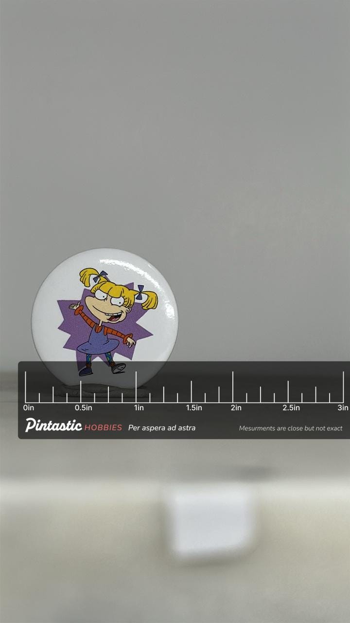 Vintage Rugrats Angelica Button Pin: Glossy White Finish - 90s Cartoon Accessory with ruler overlay for size reference