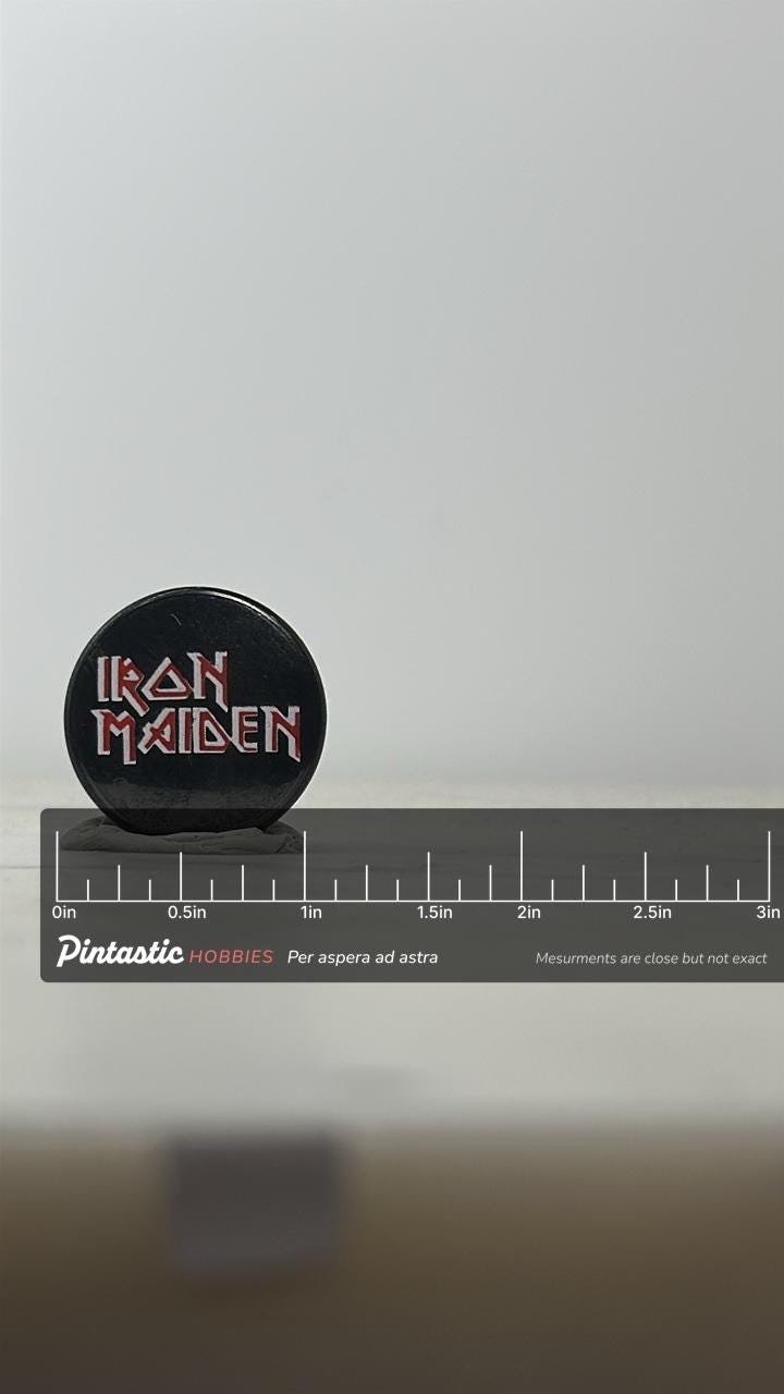 Iron Maiden Band Pin: Black & Red Logo - Vintage Rock Accessory with ruler overlay for size reference