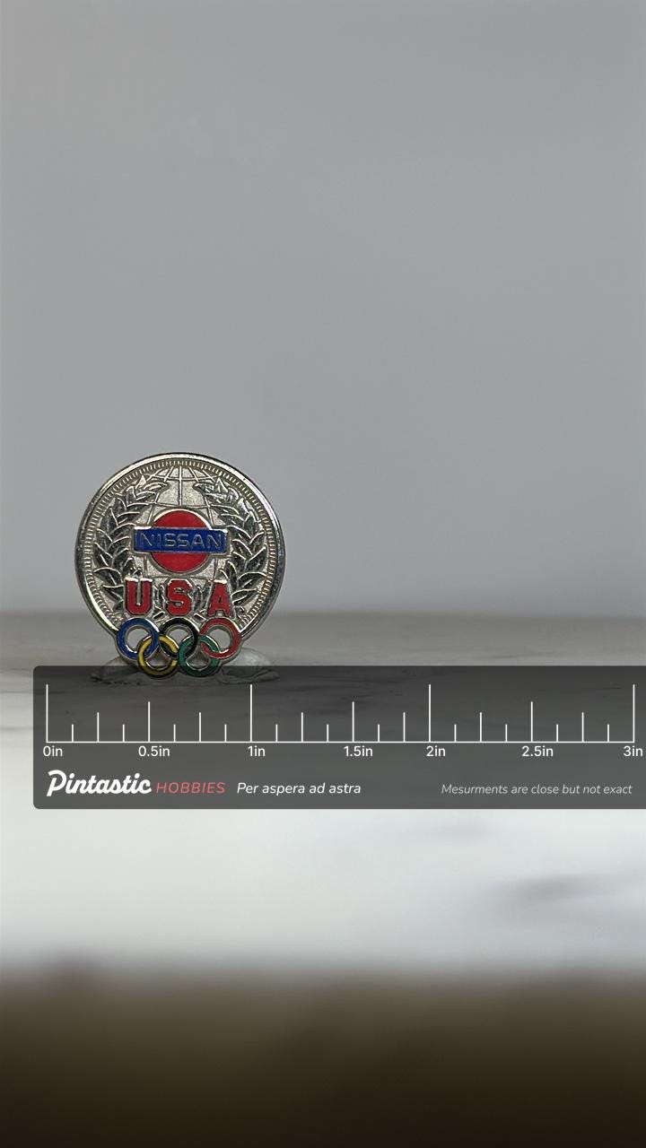 Nissan USA Olympic Pin: Silver Tone Enamel - Vintage Sports Accessory with ruler overlay for size reference