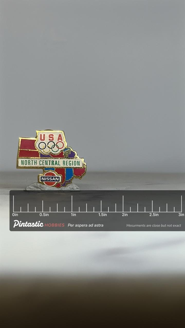 USA Olympics Nissan Pin: Multicolor Enamel - 1990s Sports Accessory with ruler overlay for size reference