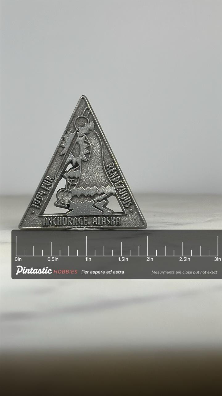 1994 Fur Rendezvous Pin: Triangular Pewter Finish - Alaska Festival Accessory with ruler overlay for size reference