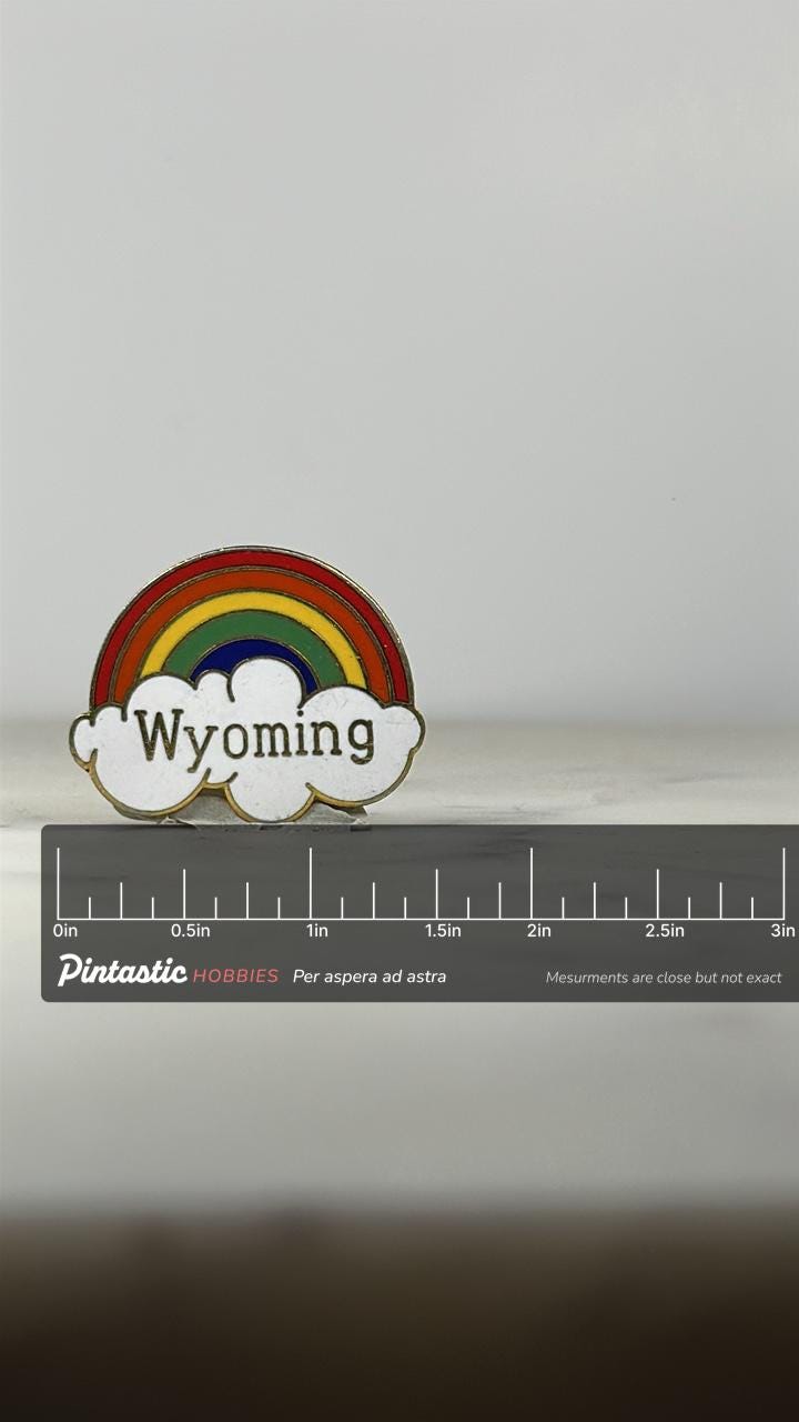 Wyoming Souvenir Pin: Rainbow Enamel - Retro Travel Accessory with ruler overlay for size reference