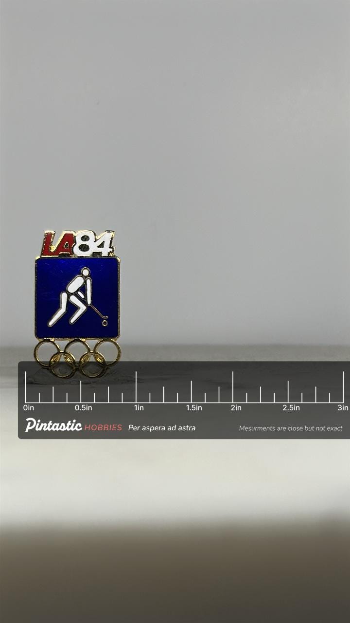 LA 1984 Olympic Field Hockey Pin: Blue Enamel & Gold Finish - Vintage Sports Accessory with ruler overlay for size reference