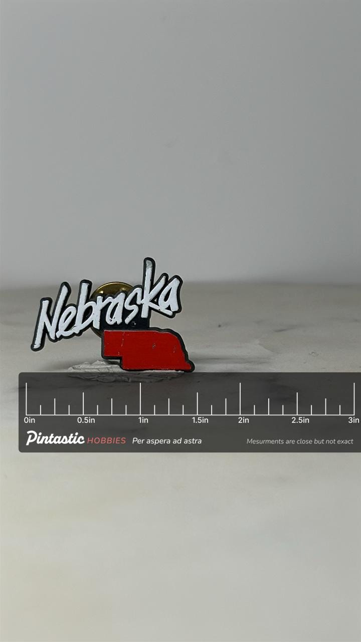 Nebraska State Lapel Pin: Red & White Enamel - Vintage Travel Accessory with ruler overlay for size reference
