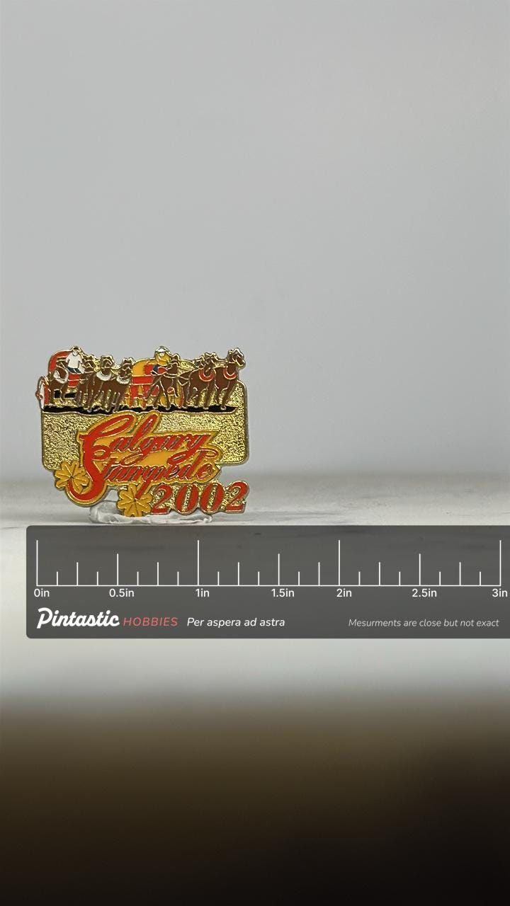 Calgary Stampede Pin: Gold Red Enamel - 2002 Rodeo Souvenir Accessory with ruler overlay for size reference