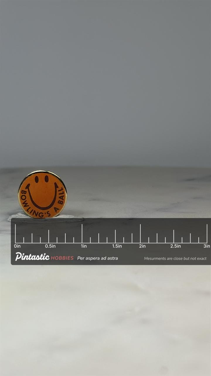 Bowling Smile Face Pin: Yellow Enamel Round - Retro Humor Accessory with ruler overlay for size reference