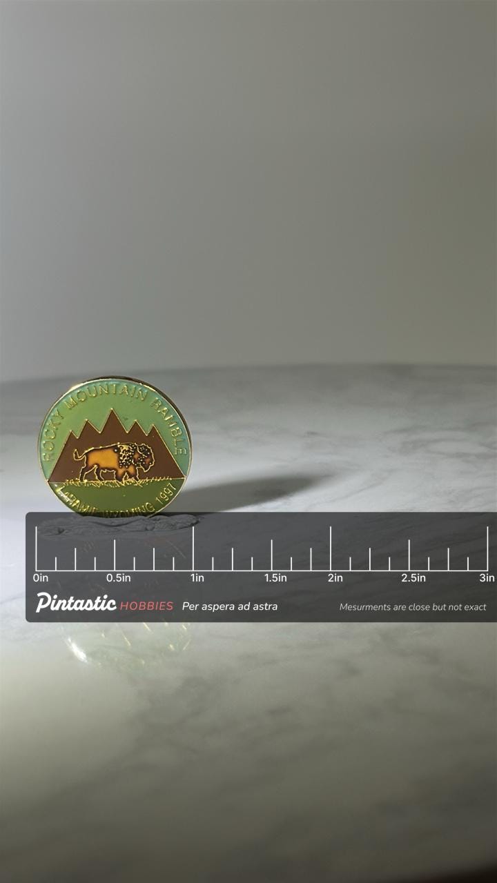 Rocky Mountain Ramble Pin: Green & Brown Enamel - 1997 Laramie Souvenir with ruler overlay for size reference