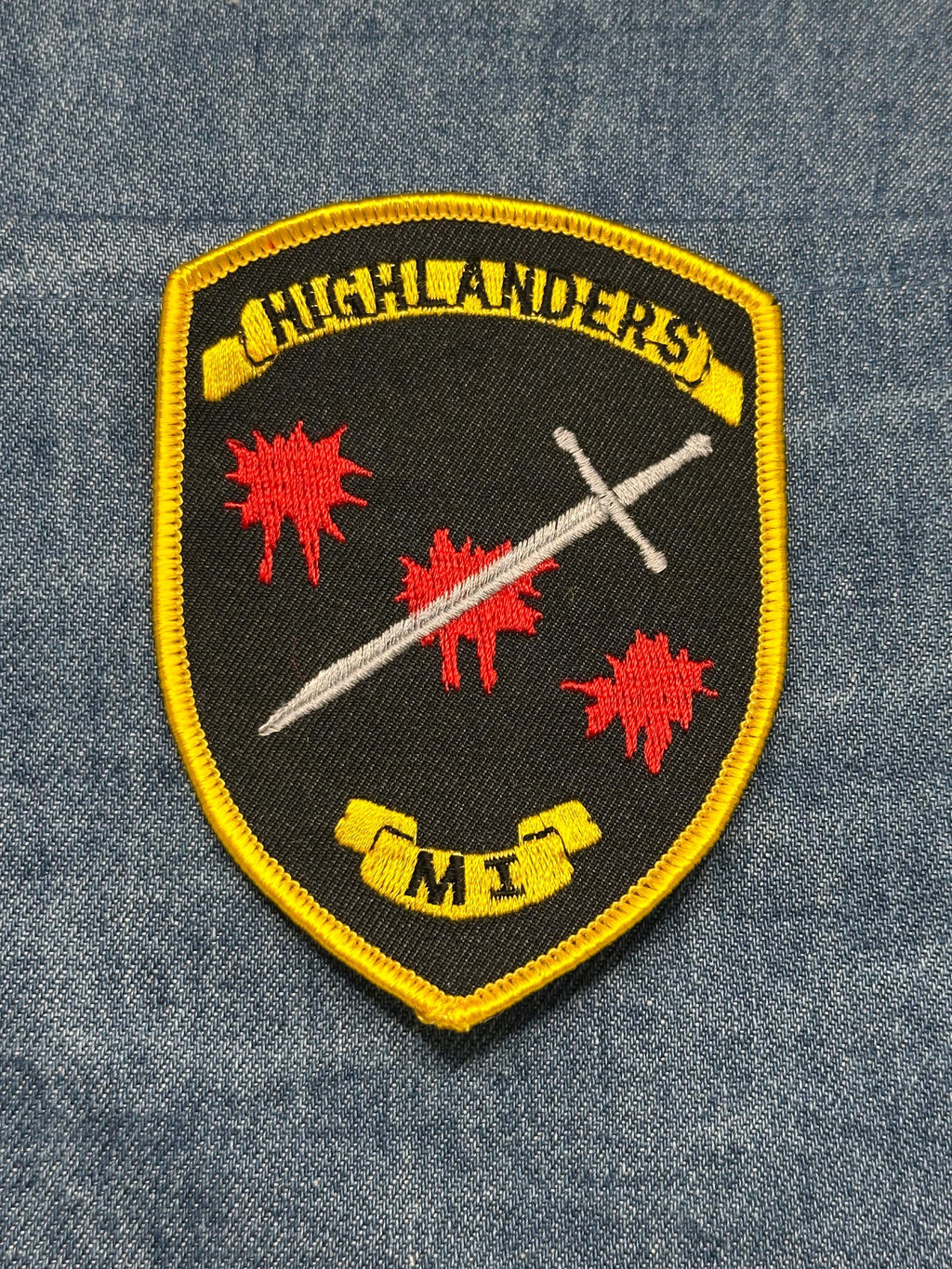 Highlanders ME Paintball Patch: Sew-On Black/Yellow Shield - Military Accessory
