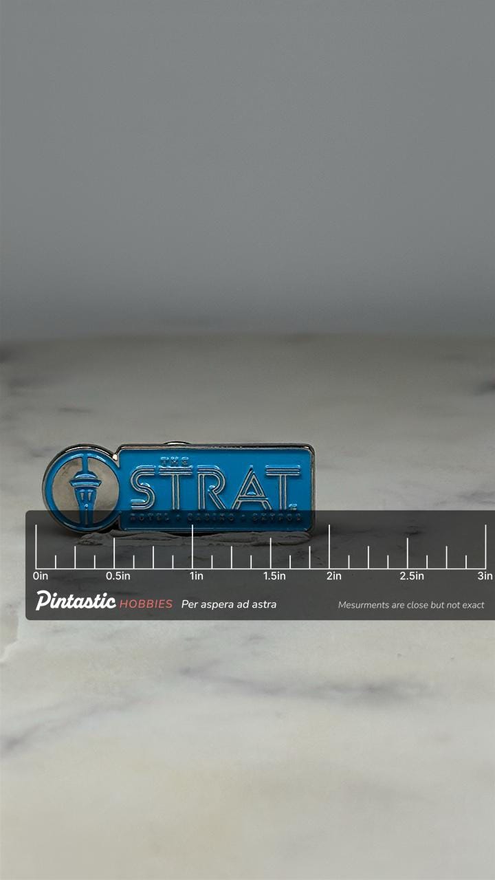The STRAT Hotel Casino Pin: Sky Blue Enamel - Las Vegas Souvenir Accessory with ruler overlay for size reference