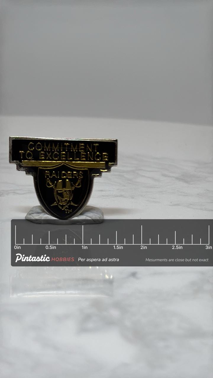 Raiders Football Pin: Black & Gold Enamel - Vintage Sports Accessory with ruler overlay for size reference