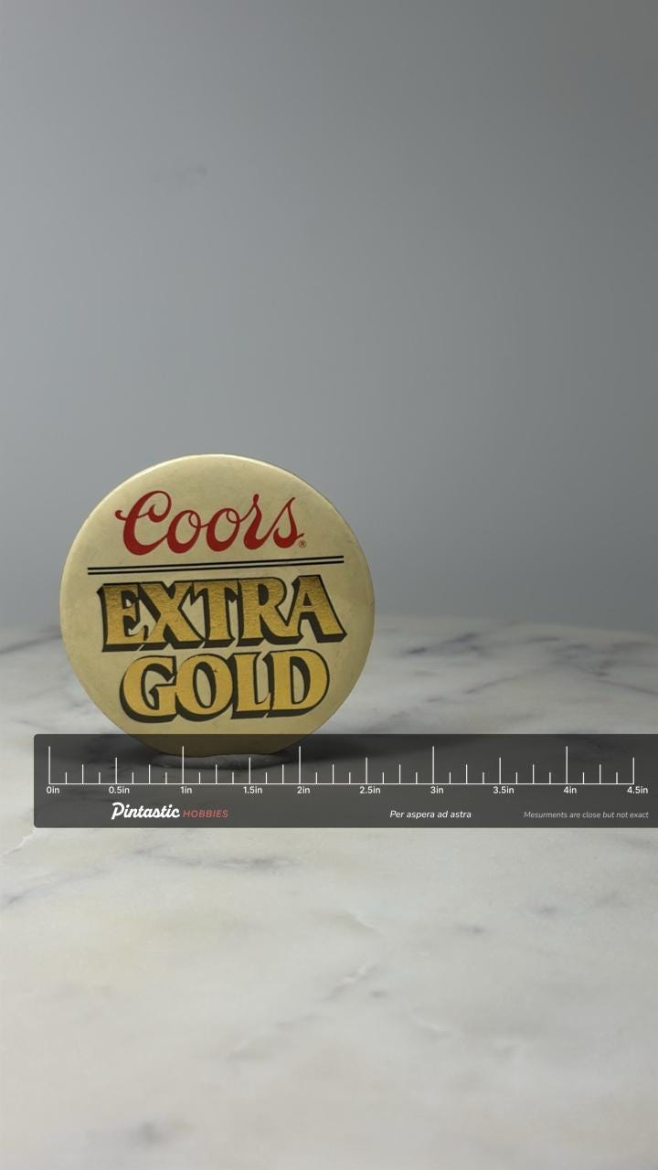 Coors Extra Gold Beer Button Pin: Cream & Gold Logo - 1980s Bar Accessory with ruler overlay for size reference