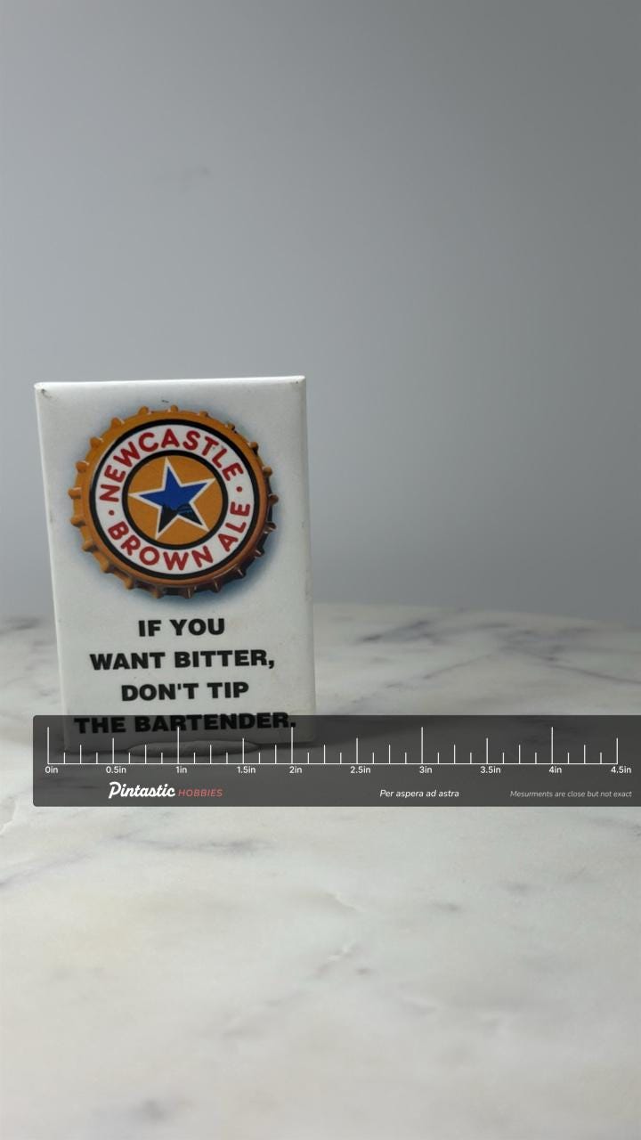 Newcastle Brown Ale Bottlecap Button Pin: Gold Enamel - Beer Brand Accessory with ruler overlay for size reference