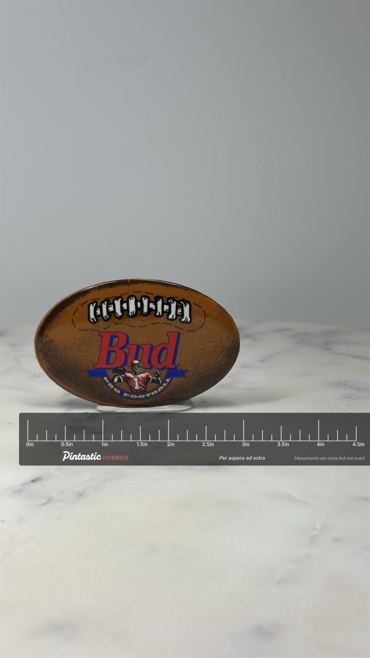 Bud Pro Football Enamel Pin: Brown Football Design - 1990s Sports Accessory with ruler overlay for size reference