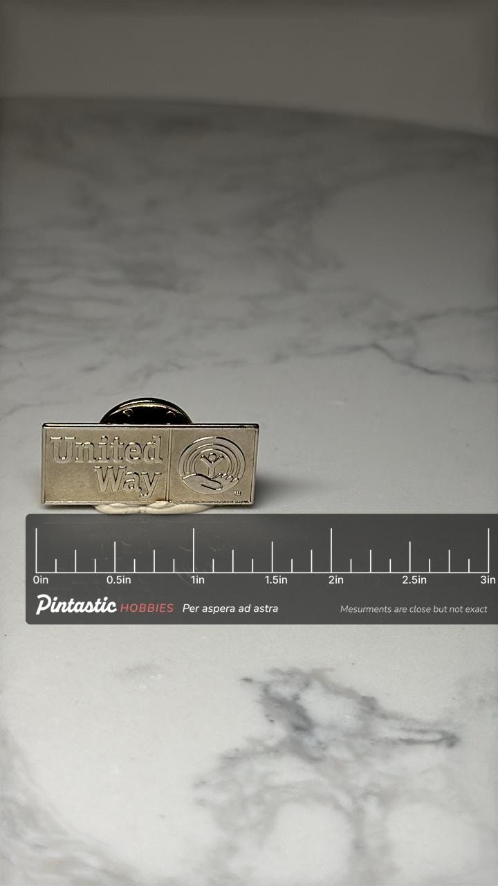 United Way Logo Pin: Gold Tone Corporate Charity Accessory with ruler overlay for size reference