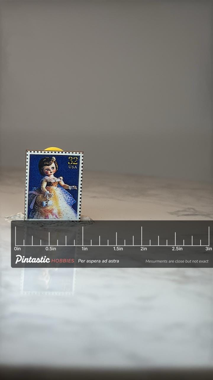 Vintage USA Doll Postage Stamp Enamel Pin: Multicolor - 1990s Accessory with ruler overlay for size reference