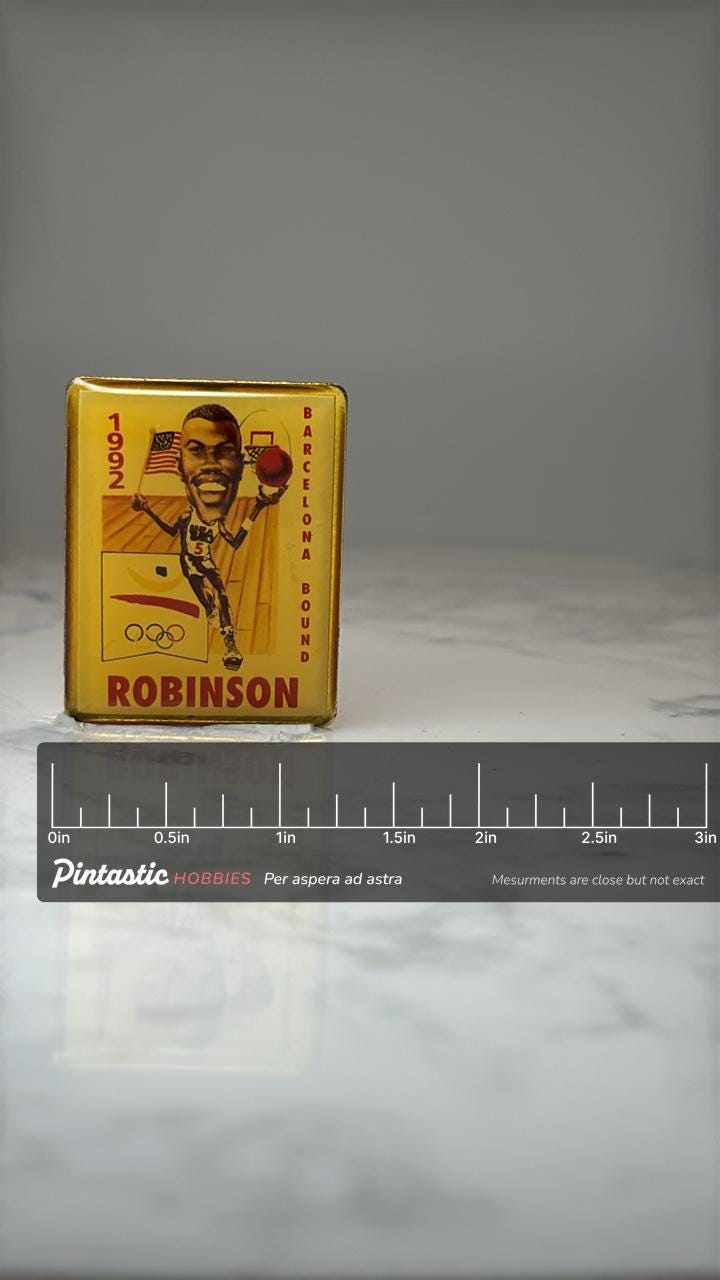 1992 Barcelona Robinson Basketball Pin: Gold Tone - Olympic Era Accessory with ruler overlay for size reference
