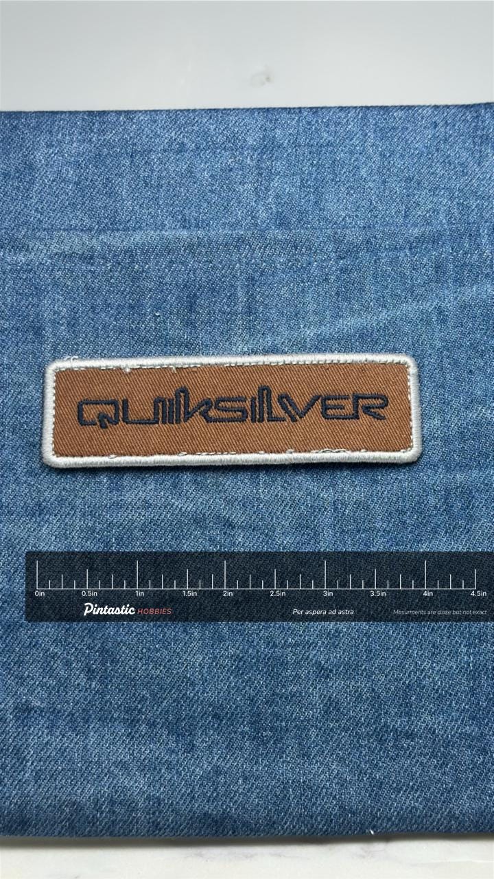 Quiksilver Logo Patch: Brown & Navy - Surf Brand Accessory with ruler overlay for size reference
