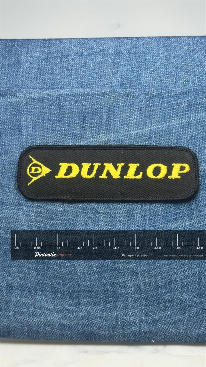 Dunlop Logo Patch: Black & Yellow - Racing Accessory with ruler overlay for size reference