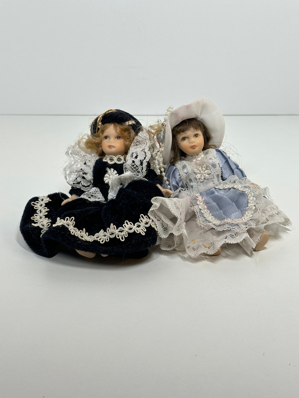 Set of two miniature porcelain dolls wearing blue vintage style lace dresses with painted faces